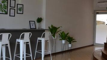 A reception area with a counter, framed botanical prints, and potted plants.