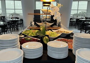 A buffet setup with various dishes and a central floral arrangement. - Encantos Golden Hotel (Sao Jose)