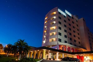 A multi-story hotel with a prominent 'HOTEL' sign, a well-lit entrance, and a parking area. - Encantos Golden Hotel (Sao Jose)