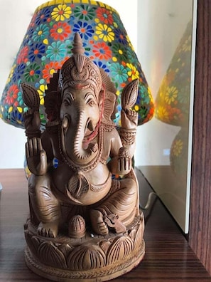 A serene sculpture of a seated deity adorns the space, accompanied by a lamp with a floral-patterned shade.