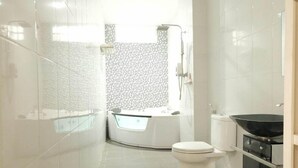 A modern bathroom with a bathtub, toilet, and a small kitchen area with a wok. - Ebizz Hotel Jember (Jember)