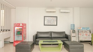 A modern living room with a grey sofa, a green coffee table, and a red Coca-Cola refrigerator. - Ebizz Hotel Jember (Jember)