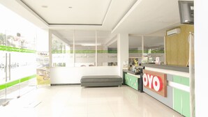 A hotel reception area with a modern design, a reception desk, and a bench. - Ebizz Hotel Jember (Jember)