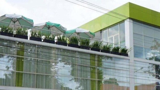 A modern building with a glass facade, green awnings, and a flat roof. - Ebizz Hotel Jember (Jember)