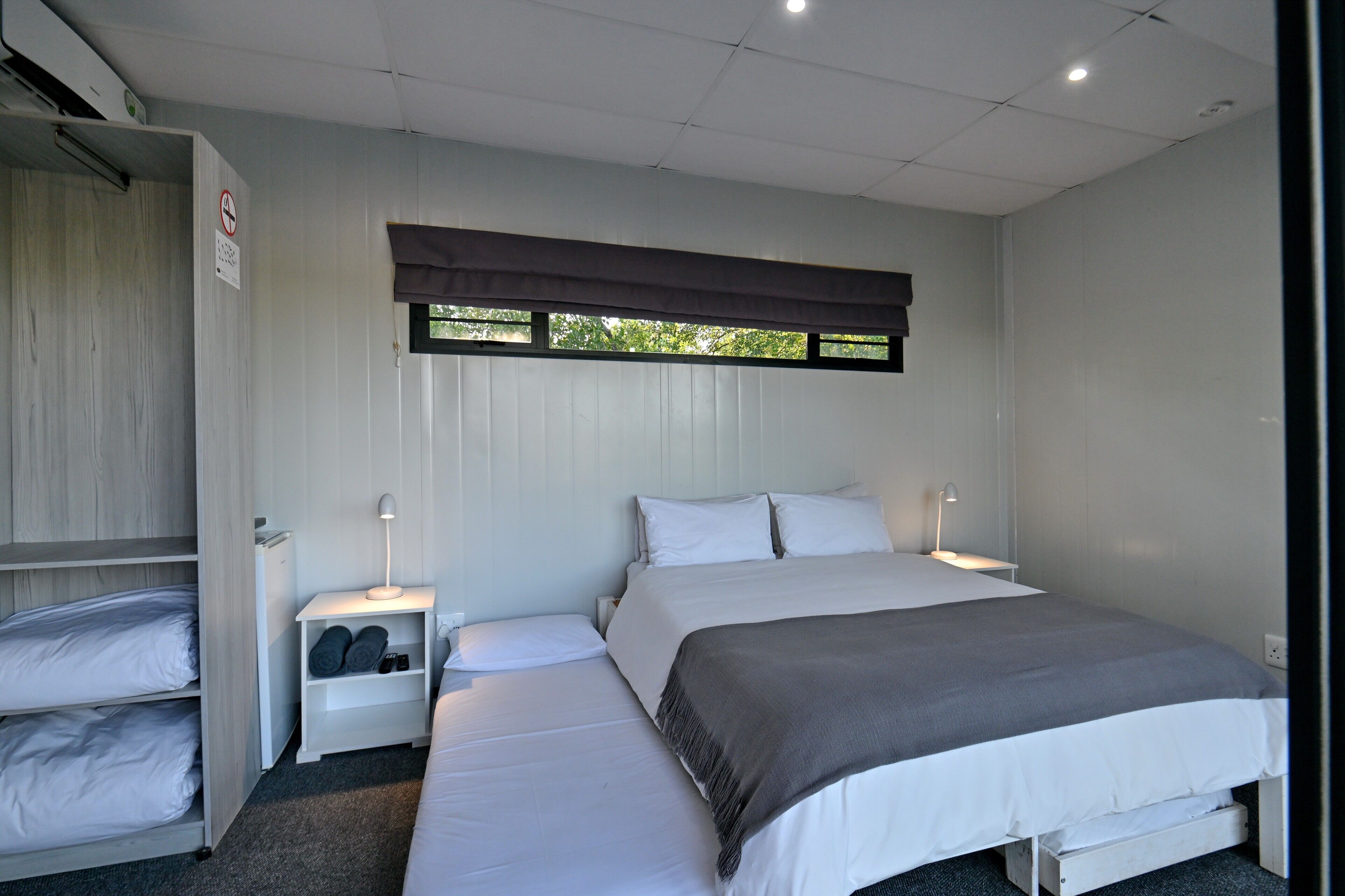 Un dormitorio con cama, mesitas de noche, armario y ventana con persianas.