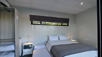 Un dormitorio con cama, mesitas de noche, armario y ventana con persianas.