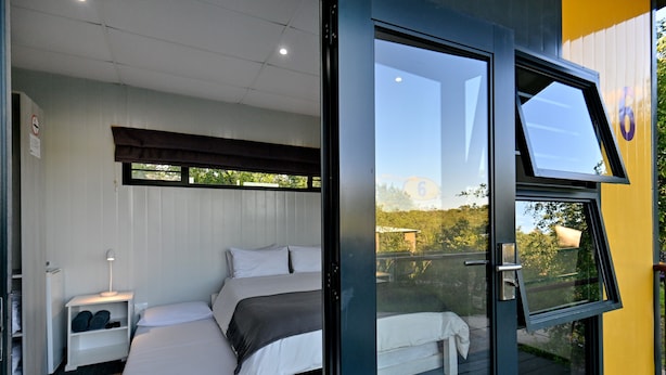 A bedroom with two beds, a nightstand, and a window with a view of the outdoors.