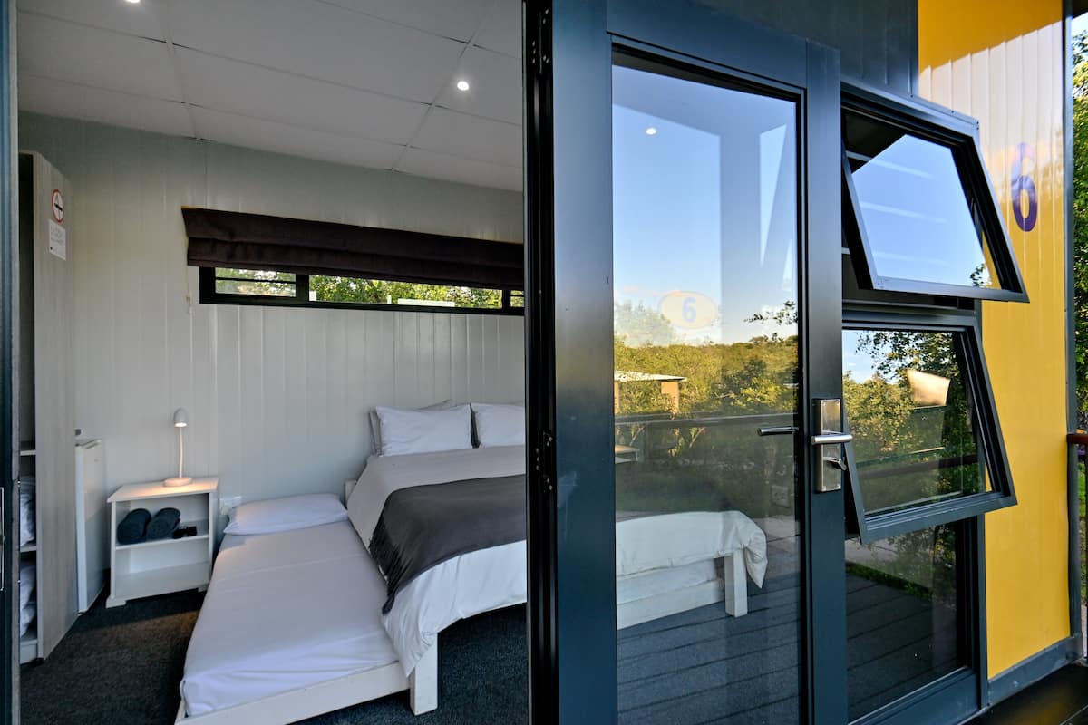 Un dormitorio con dos camas, una mesita de noche y una ventana con vistas al exterior.