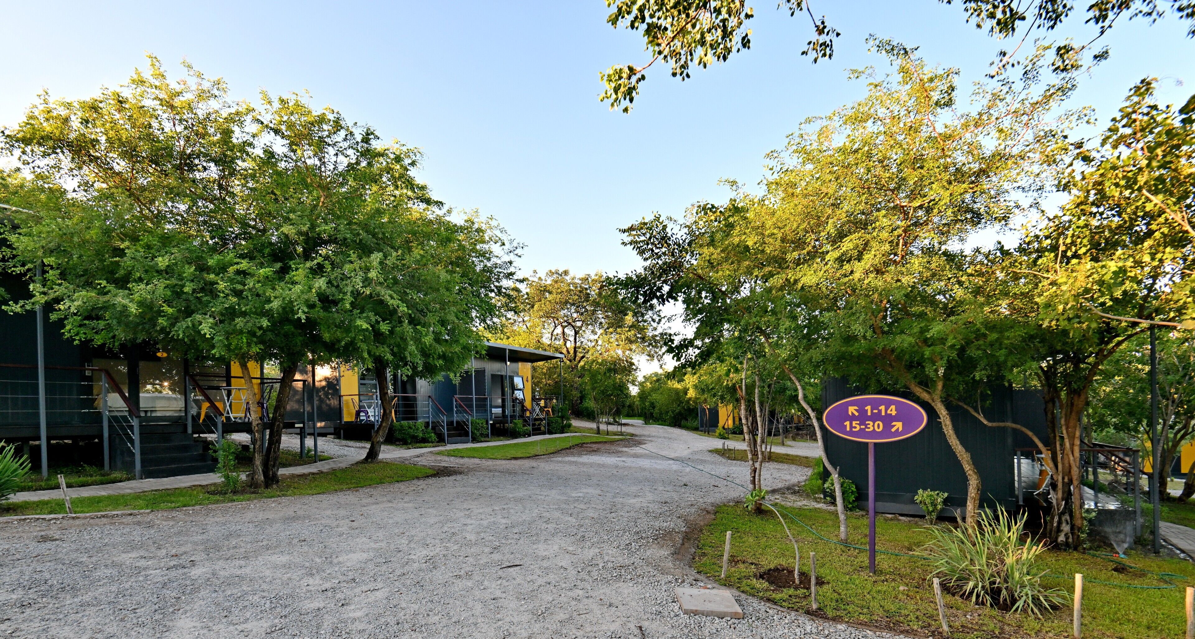 A gravel driveway leading to a building with a sign indicating parking availability.