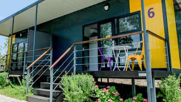 Un edificio moderno con una escalera, una pequeña zona de estar al aire libre con sillas y el número 6 en la fachada.