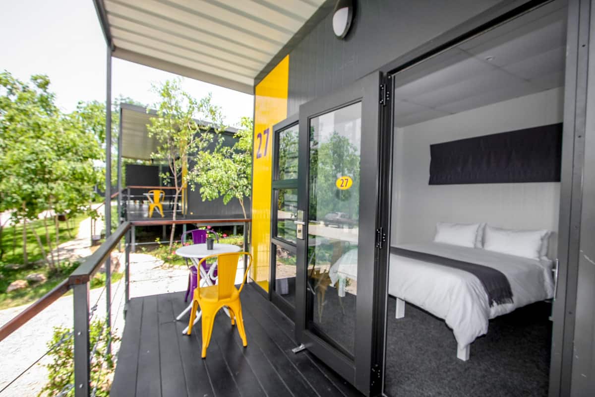 Una habitación de hotel moderna con un amplio ventanal corredero que da a un espacio exterior con una mesa y sillas.