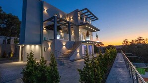 A modern two-story house with a balcony, a staircase, and a well-lit exterior. - Five Stars Villa Corfu (Corfu)