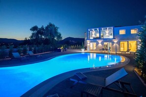 A modern house with a swimming pool, outdoor seating, and a mountain view.