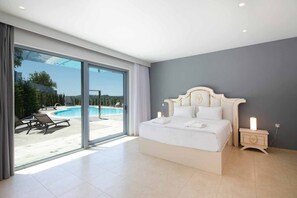 A bedroom with a large bed, a nightstand, and a view of a swimming pool.