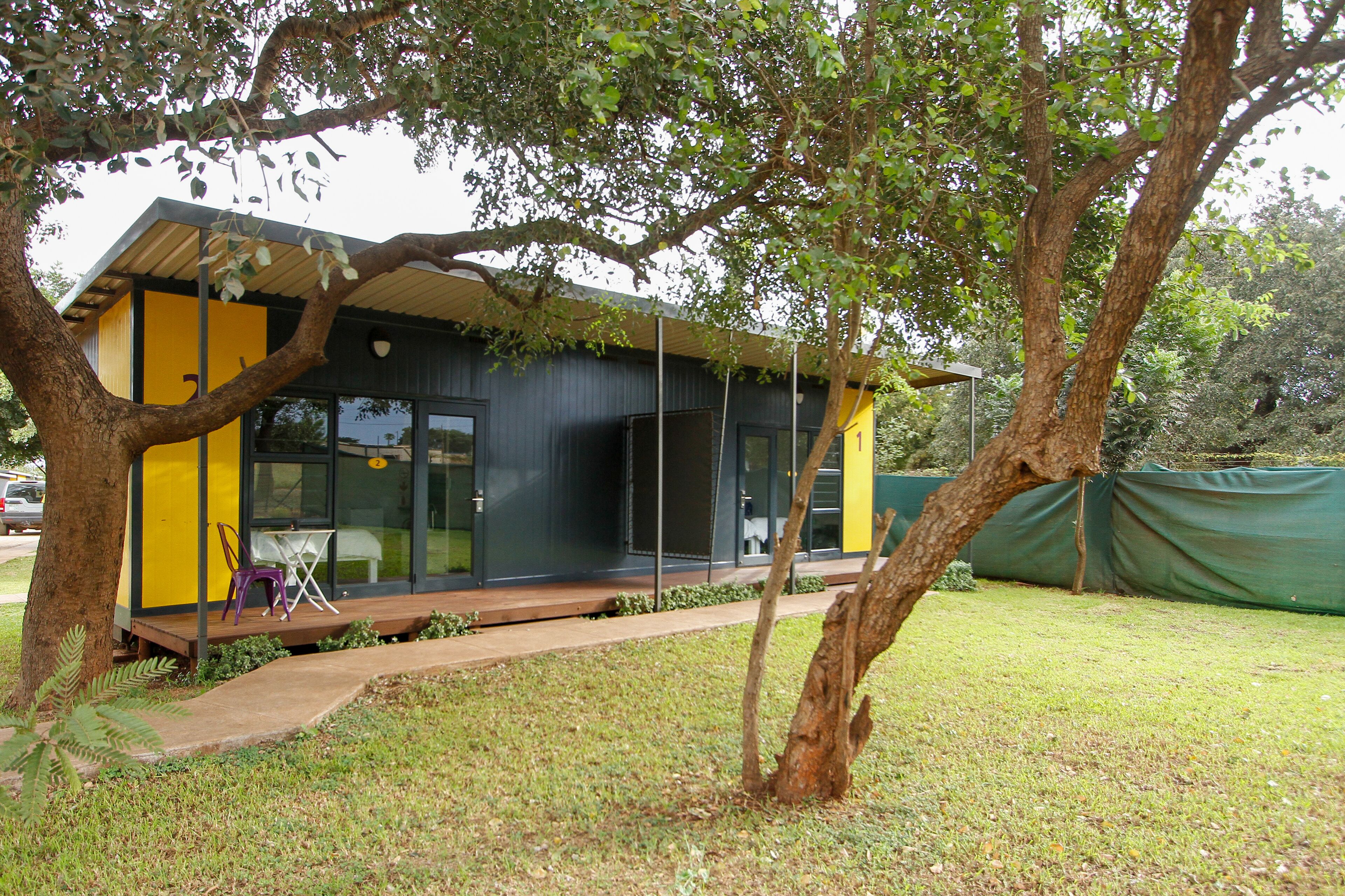 A modern building with a yellow and black facade, large windows, and a covered outdoor seating area.