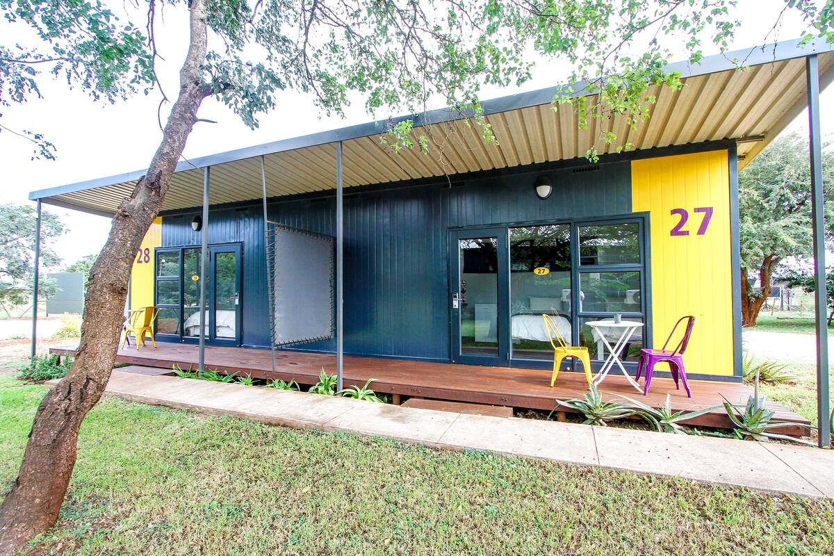 A modern building with a covered porch, numbered 27, featuring large windows and outdoor seating.