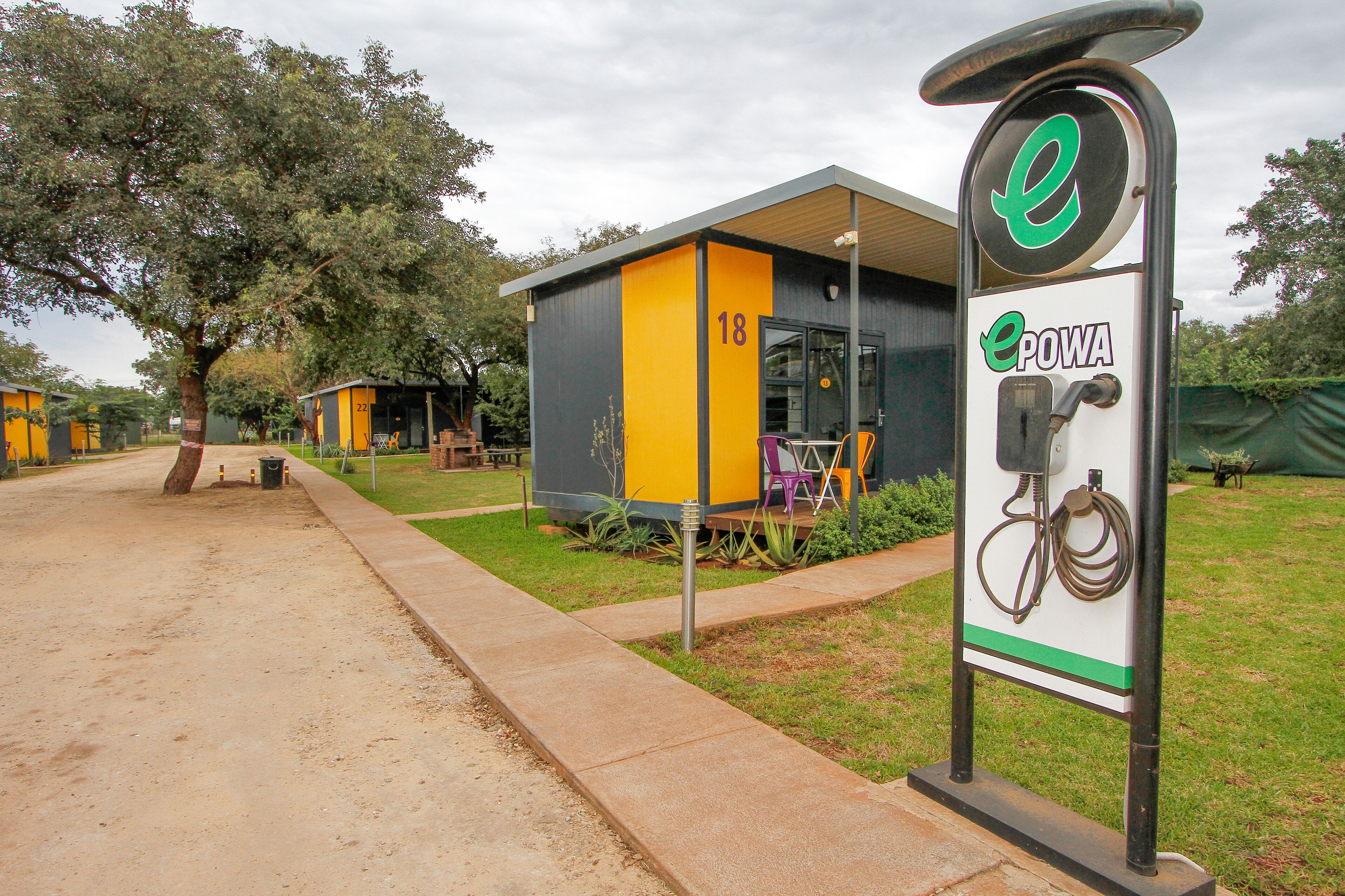 A modern building with a yellow and gray facade, a sign with a bicycle symbol, and the number 18.