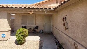 Une propriété résidentielle dotée d’une terrasse, d’un petit jardin et d’une porte avec un portail.