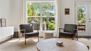 A room with two chairs, a round table, and a large window with a view of greenery.