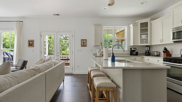 A modern kitchen with white cabinetry, a large island, and a seating area with a sofa and stools.