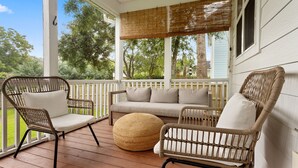 A covered porch with wicker furniture and a cushioned bench.