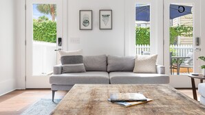 Una sala de estar moderna con un sofá gris, una mesa de centro de madera y obras de arte enmarcadas en la pared.