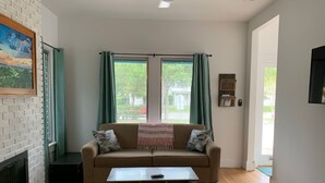 A living room with a beige sofa, a coffee table, and a fireplace. - 2-Bedroom house with a great yard in down town (New Smyrna Beach)