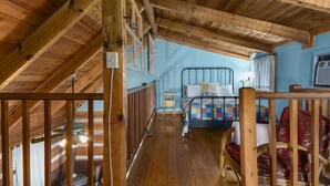 Un dormitorio estilo loft con techo inclinado, una cama con colcha, una mesita de noche y una silla.