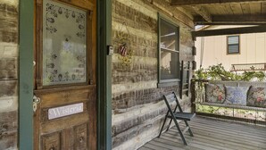 Una cabaña de madera con un porche, una banca y una puerta con la leyenda 'Wisteria'.