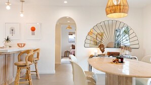 A modern kitchen with a dining area, featuring a round table, chairs, and pendant lighting.