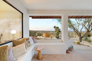 A modern interior with a seating area, a wooden table, and a view of the desert landscape.