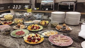 Un buffet proposant une variété de plats, notamment des fruits, des fromages et des viandes.