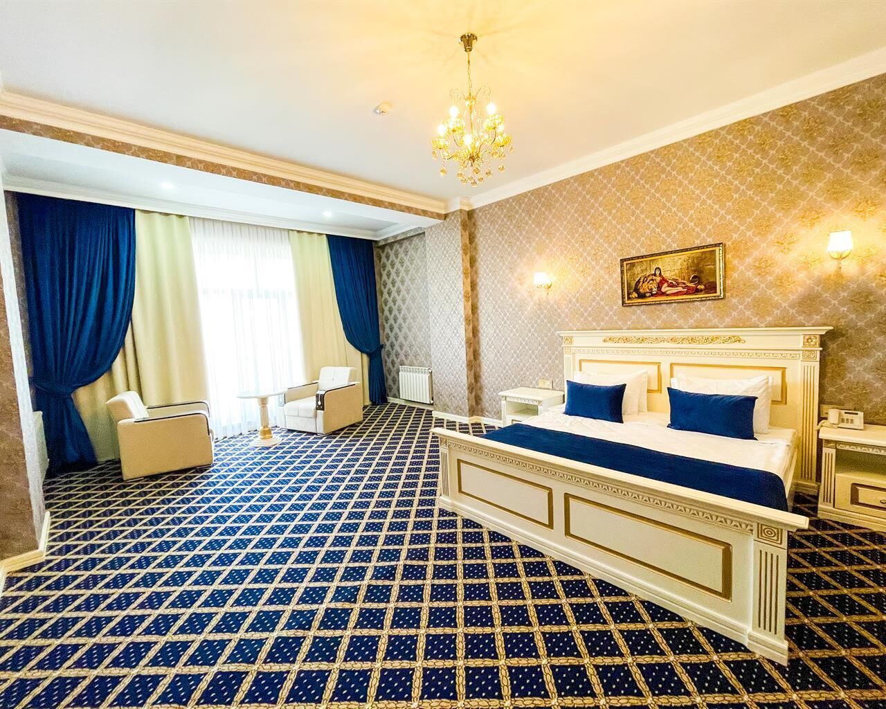 Une chambre d’hôtel avec un grand lit, une chaise, une petite table et un lustre.