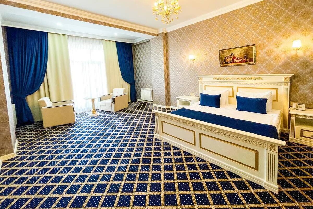 A hotel room with a large bed, a chair, a small table, and a chandelier.