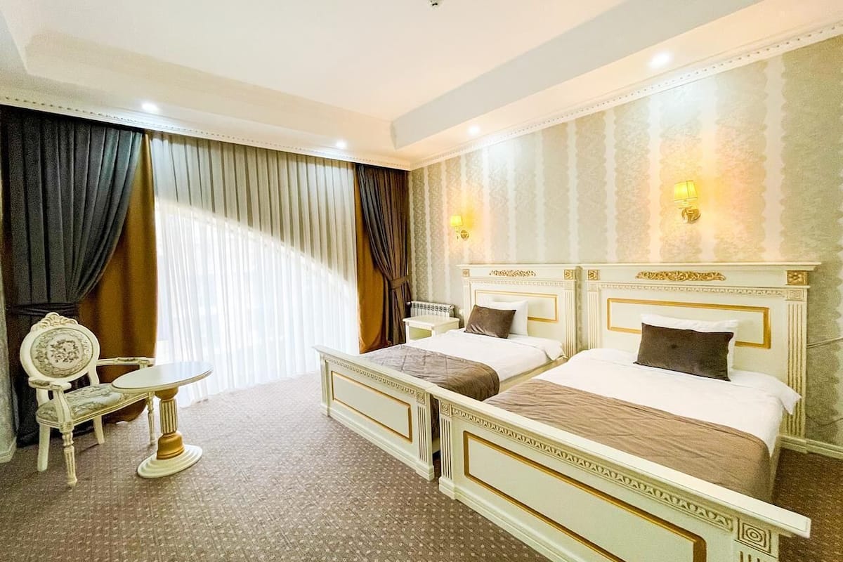 A hotel room with two beds, a small table, and a chair.