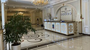 Un vaste hall d’entrée agrémenté d’un lustre, d’un comptoir de réception et d’une grande plante en pot.