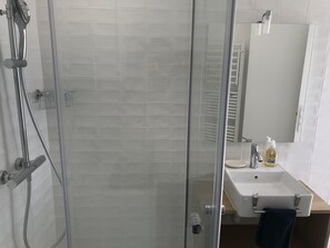 Een douche, handdoeken, zeep, toiletpapier