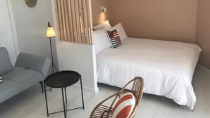 Un dormitorio con cama, sofá, una mesita y una silla.