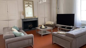 A living room with two grey sofas, a fireplace, a flat-screen TV, and a large window with curtains. - Town house with swimming pool and private garden (Pélissanne)