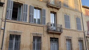 A building with multiple windows, some with shutters, and a central entrance with a door. - Town house with swimming pool and private garden (Pélissanne)