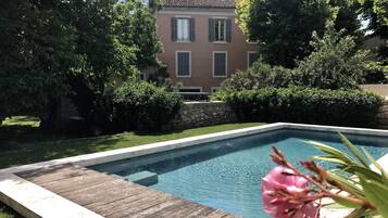 Relax by the serene pool surrounded by lush greenery and a well-maintained lawn.