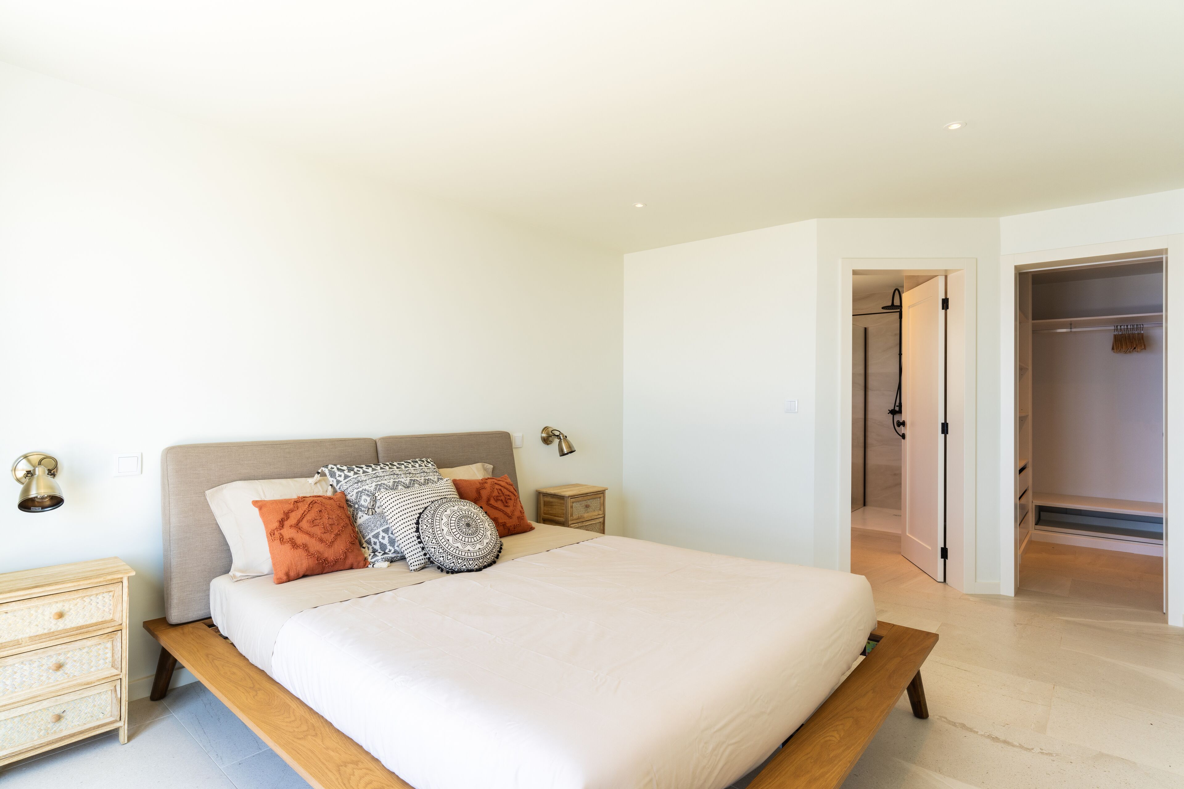 Un dormitorio con cama, mesitas de noche, armario y vestidor.