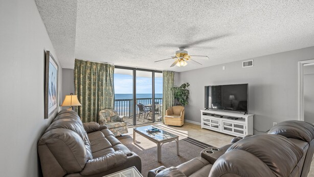 A living room with a sofa, a coffee table, a TV, and a balcony with a view of the ocean. - Ocean Bay Club 503-4BR/3BA Oceanfront condo in Ocean Drive (North Myrtle Beach)