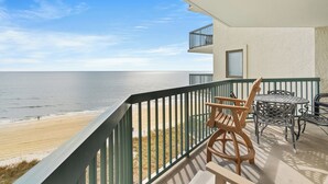 A balcony with a view of the beach and ocean.