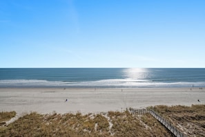 A beach with a wooden fence and a clear sky.