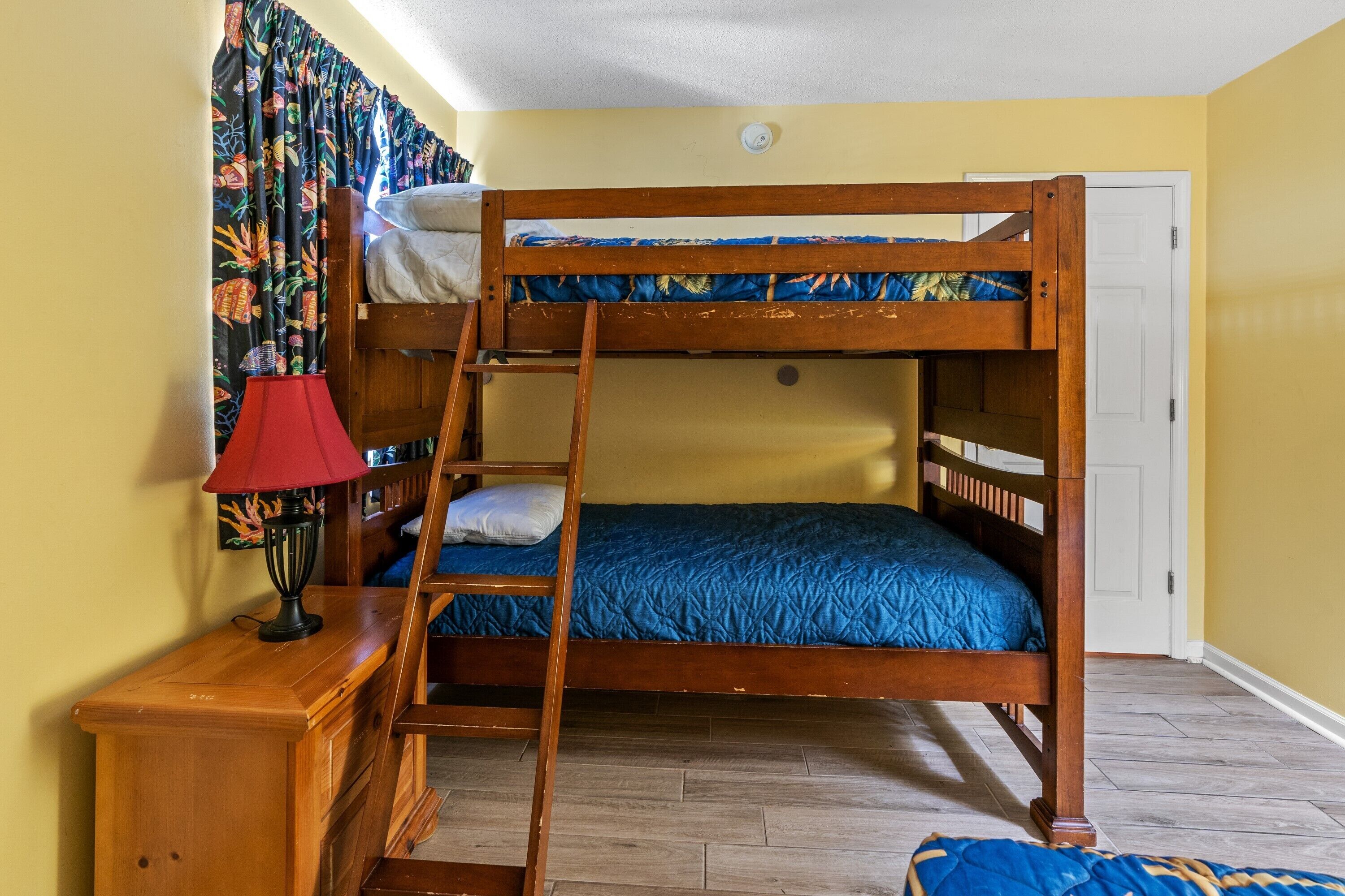 A bunk bed room with a ladder, a red lamp, and a door.