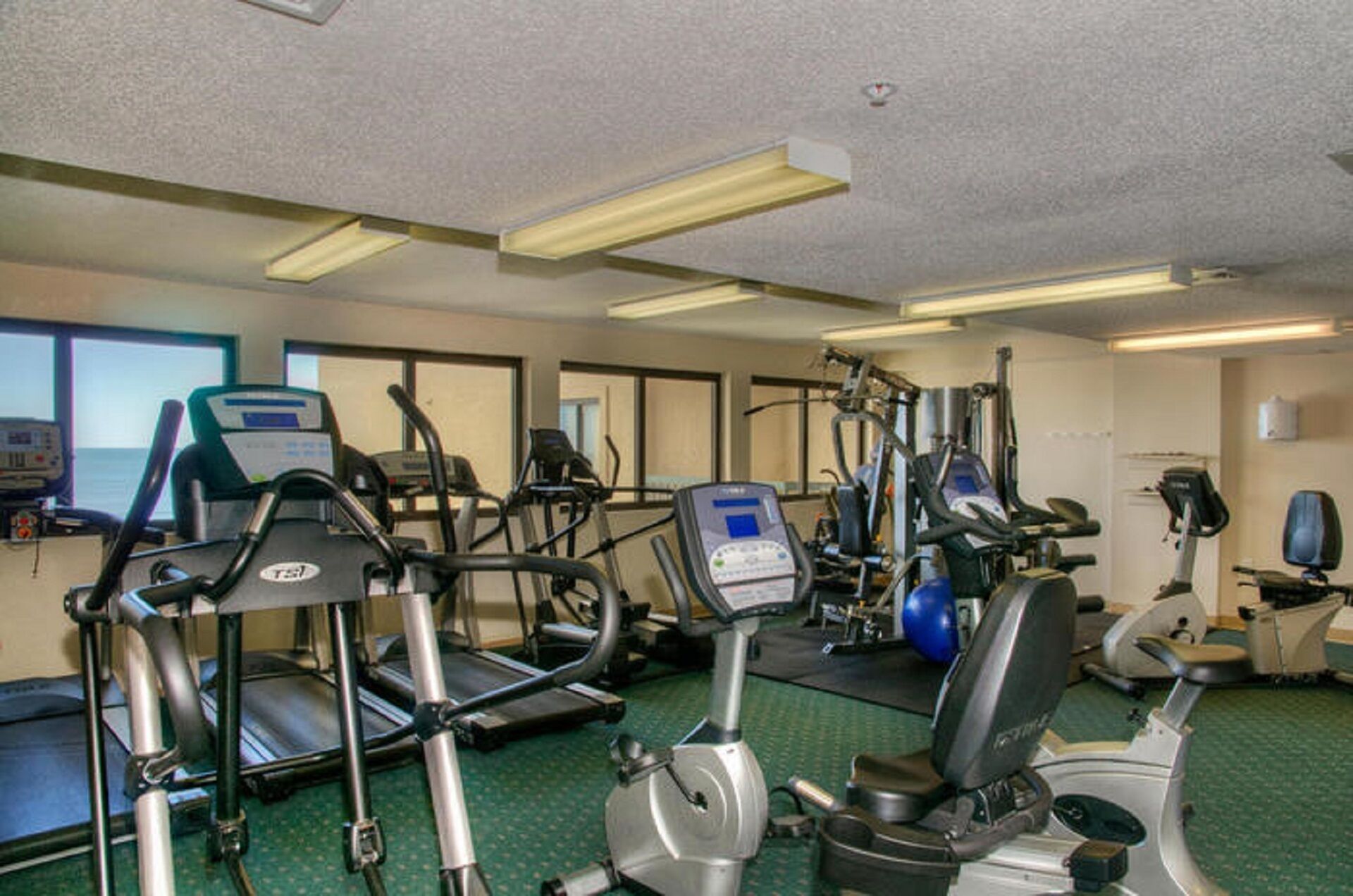 Une salle de sport équipée de tapis de course, d’appareils elliptiques et de vélos d’appartement.