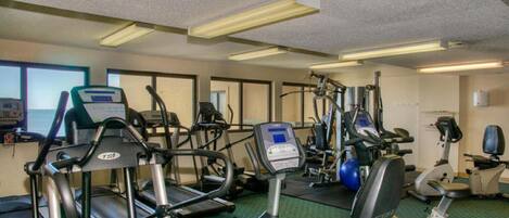 Une salle de sport équipée de tapis de course, d’appareils elliptiques et de vélos d’appartement.