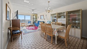A spacious living room with a dining area, a television, and a chandelier.