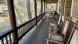 A wooden deck with rocking chairs and a view of a river.